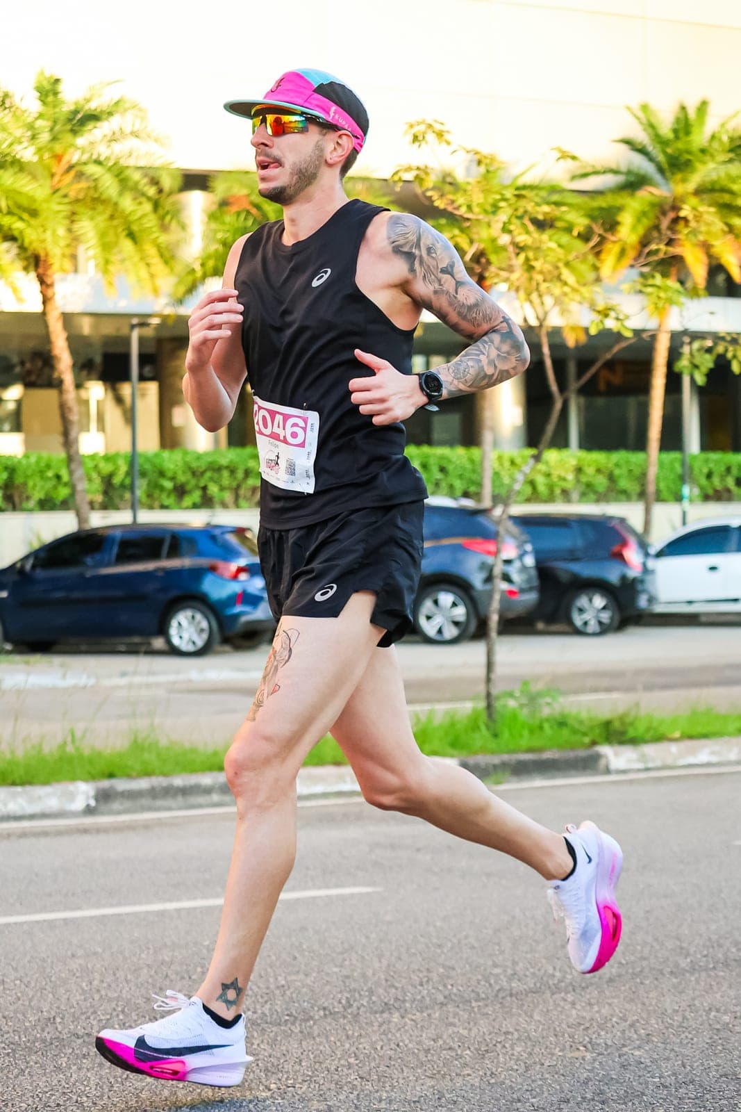 Felipe Bessa em plena passada em uma corrida de rua, de regata preta e boné rosa.